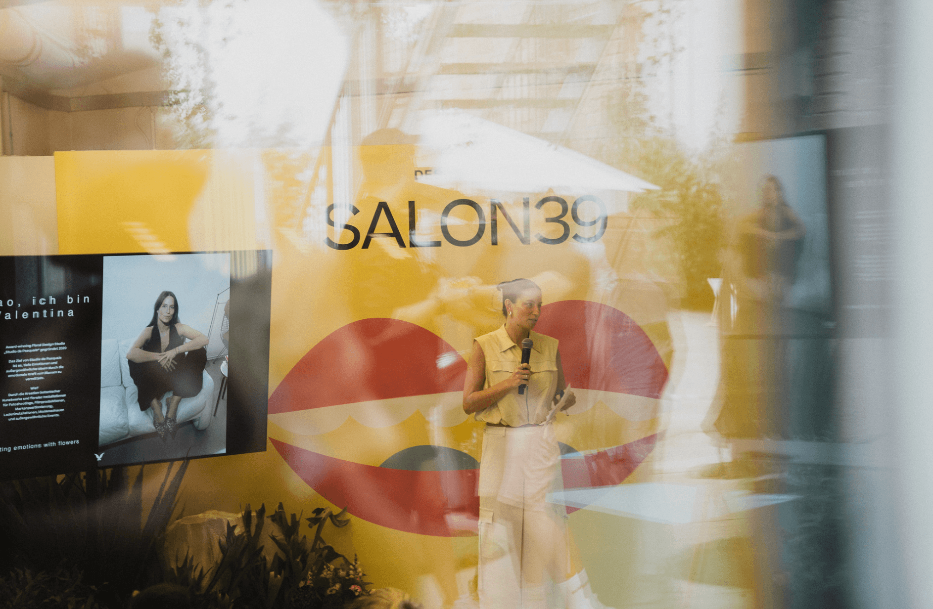 Reflexion des SALON39-Schaufensters mit Rednerin und Lippen-Grafik