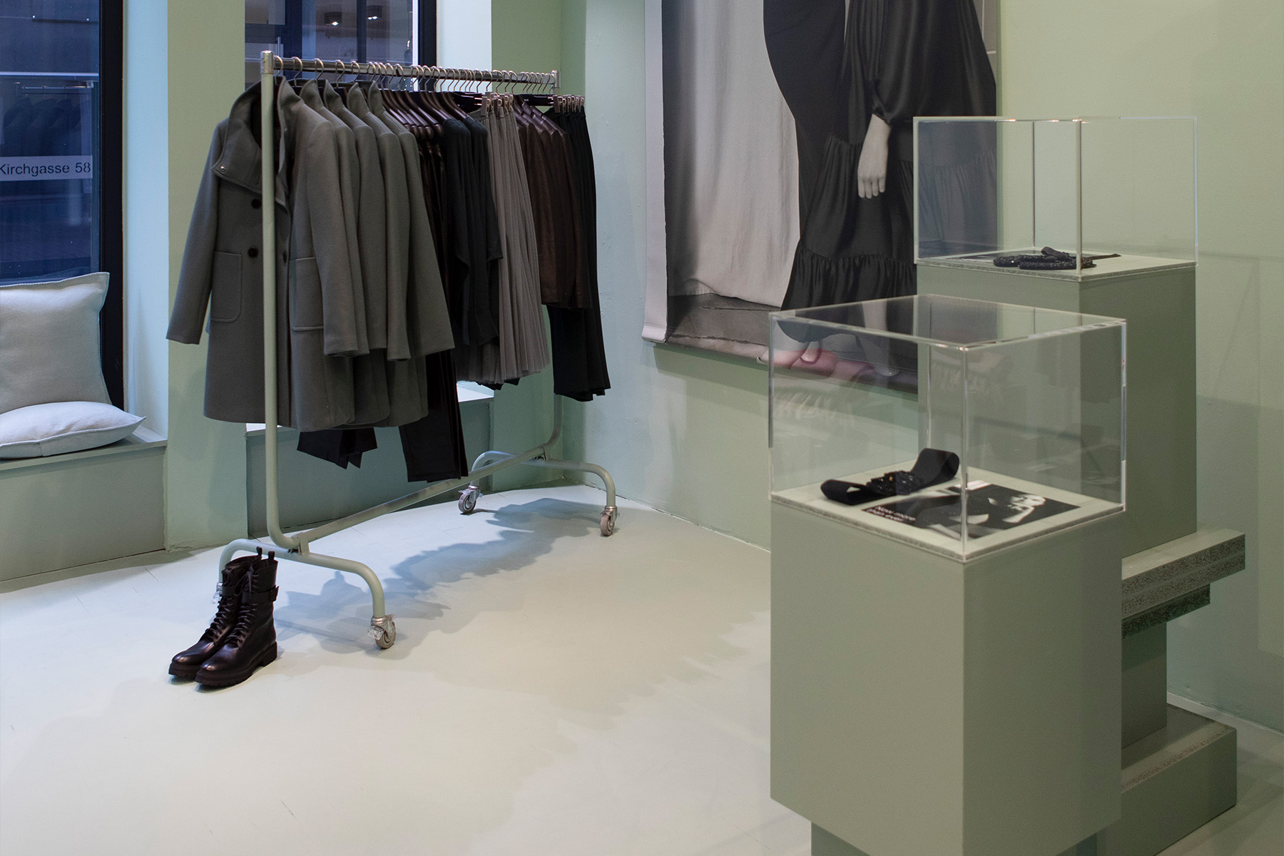 Kleiderständer und Acrylvitrinen auf lindgrünen Podesten im Hallhuber Pop-up