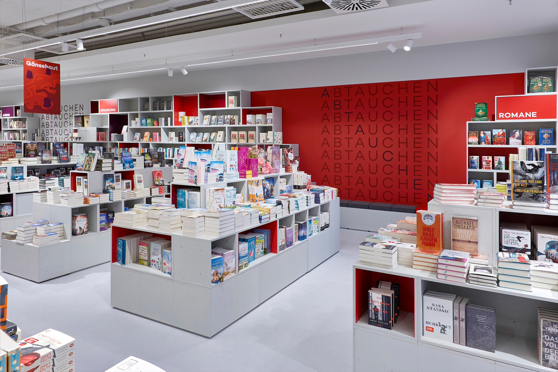 Hugendubel store with a red "Abtauchen" zone wall and book tables in the foreground.