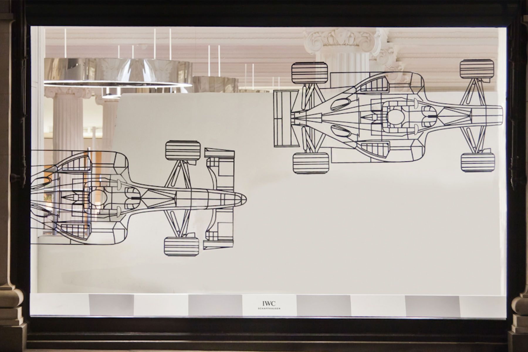 Technische Konstruktionszeichnung eines Formel-1-Rennwagens auf Glaswand mit IWC-Schaffhausen-Logo