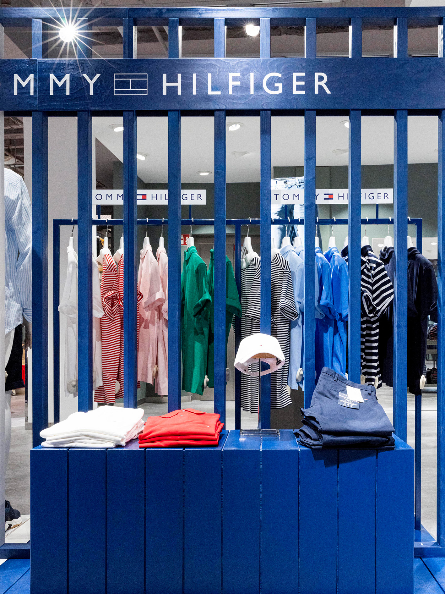 Nahaufnahme des blauen Lamellen-Displays mit gestreiften Shirts und gefalteter Ware.
