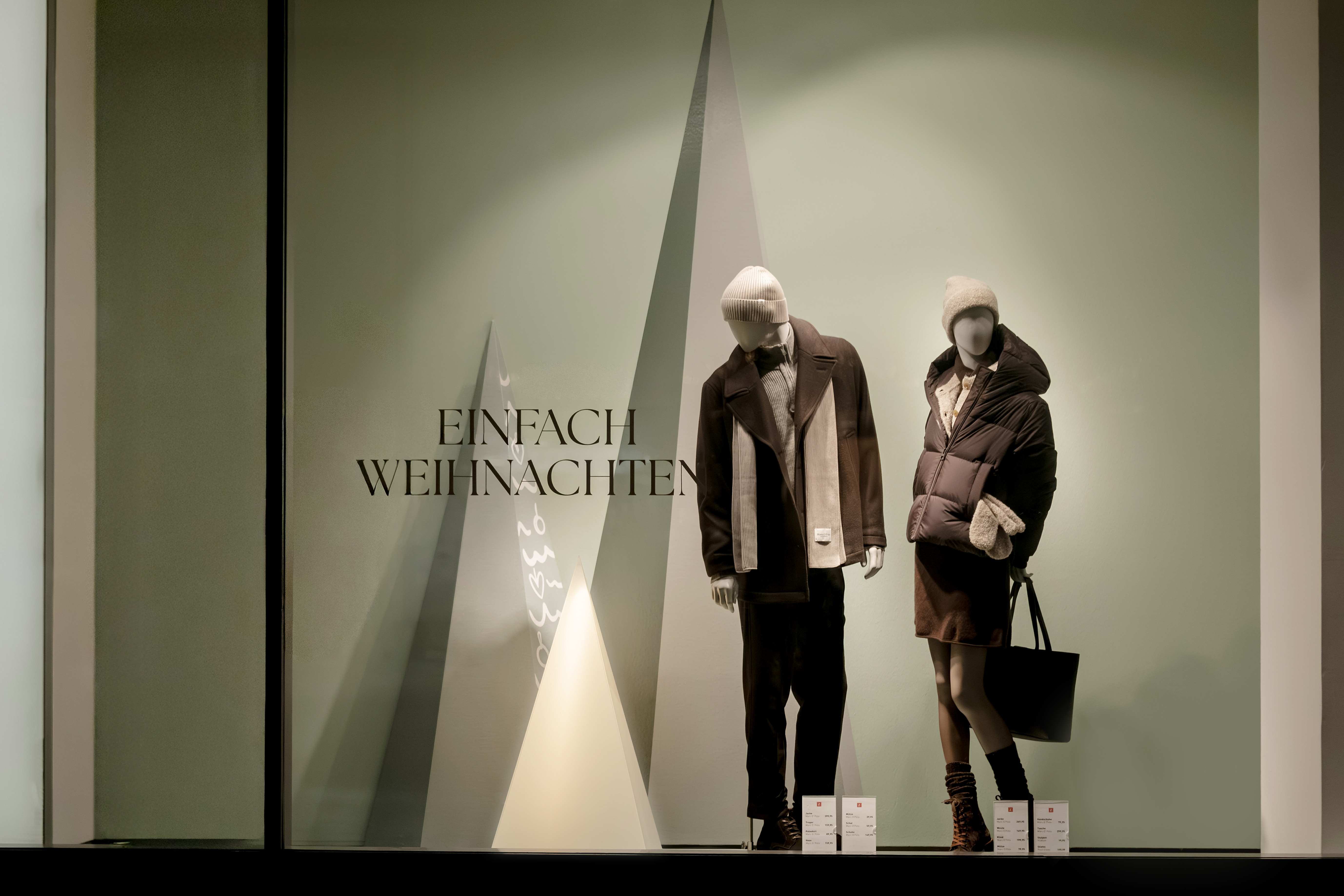Zinser-Schaufenster mit zwei Mannequins in Wintermode vor abstrakten Tannen-Dreiecken und Schriftzug „Einfach Weihnachten".