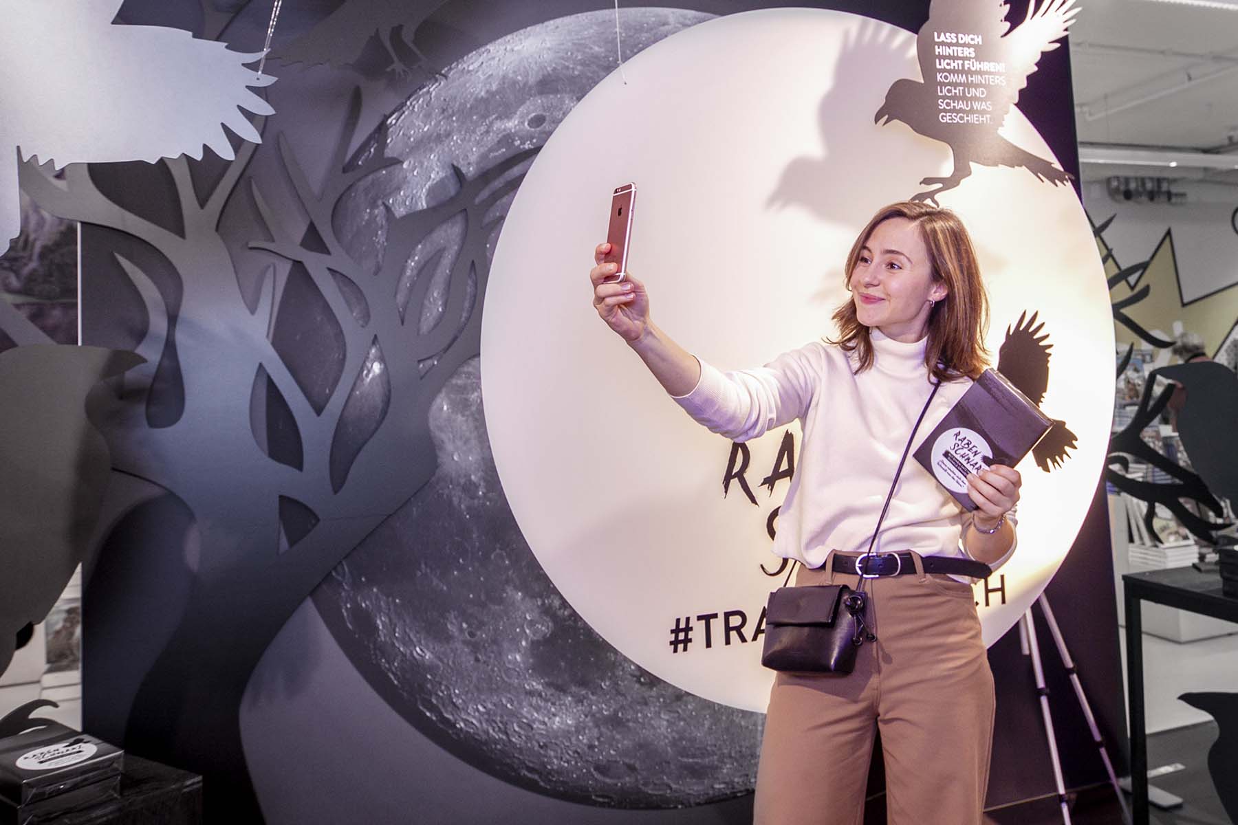 POS-Aktivierung im Buchhandel: Kundin fotografiert sich vor Mond-Kulisse mit Rabenmotiv