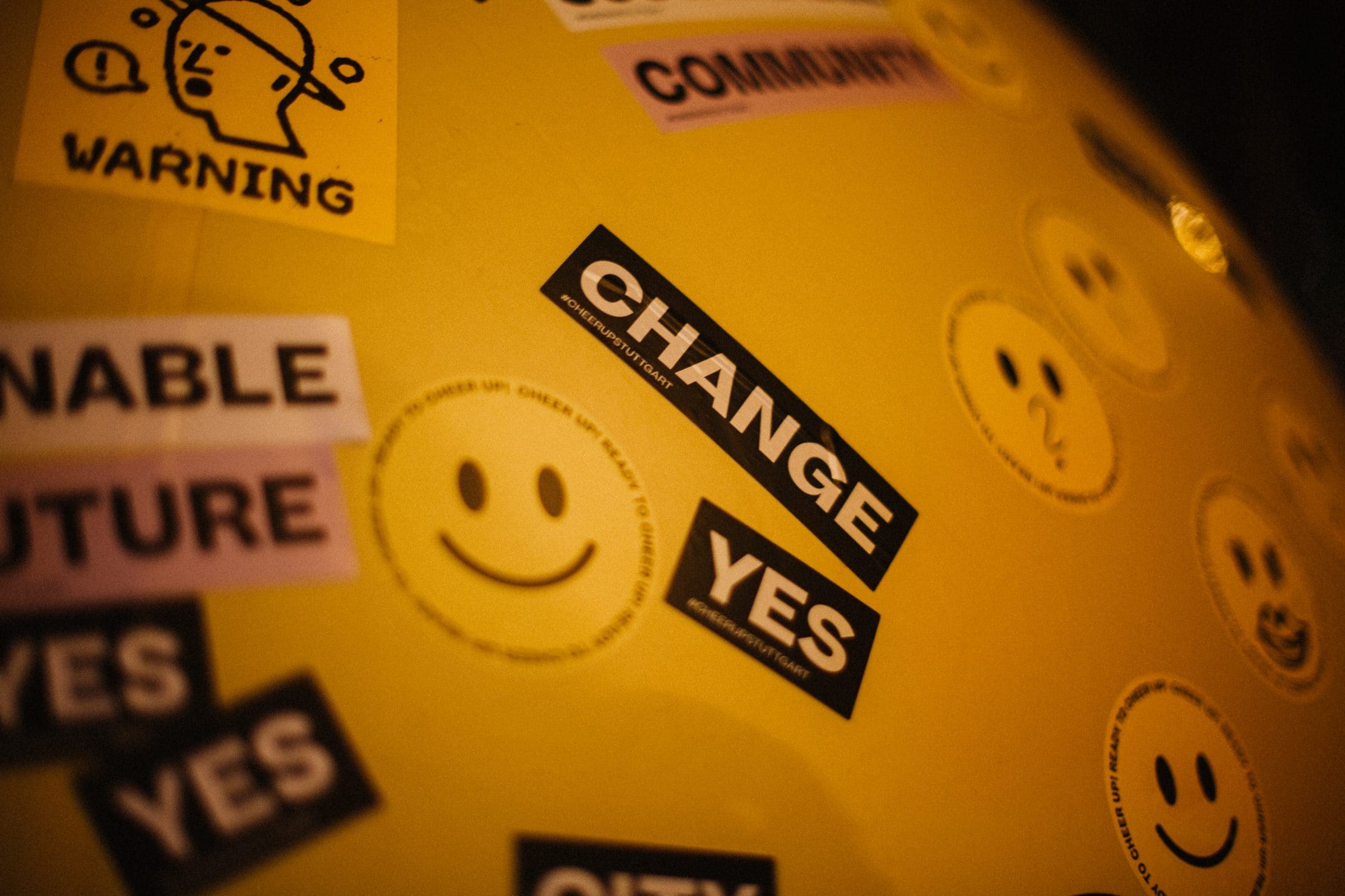 Close-up of the yellow smiley balloon covered in stickers reading “Change”, “Yes” and “Community”