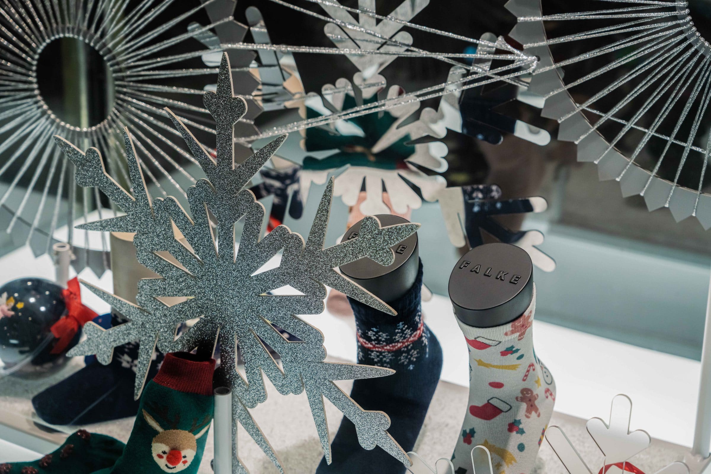 Close-up of the Falke display: silver snowflakes and Christmas socks with a reindeer motif