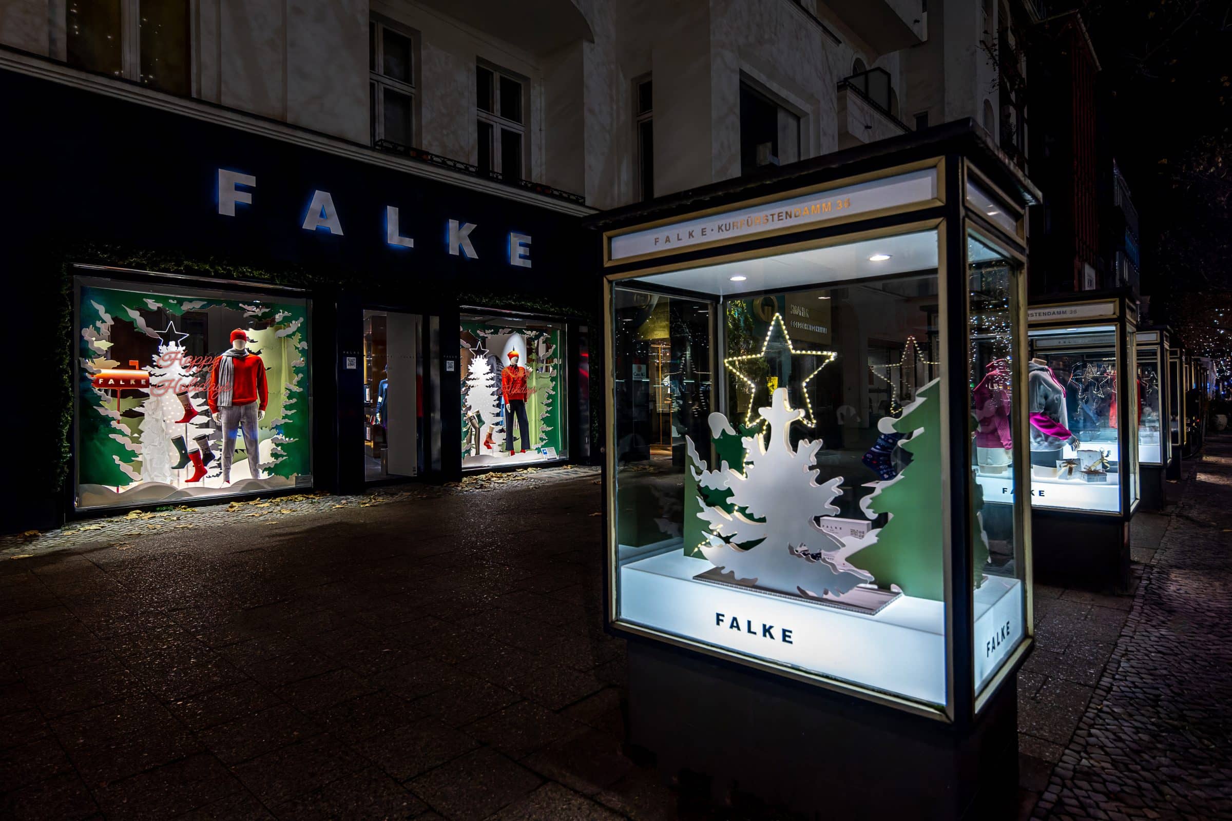 Falke-Filiale bei Nacht mit weihnachtlich dekorierten Schaufenstern und Vitrinen