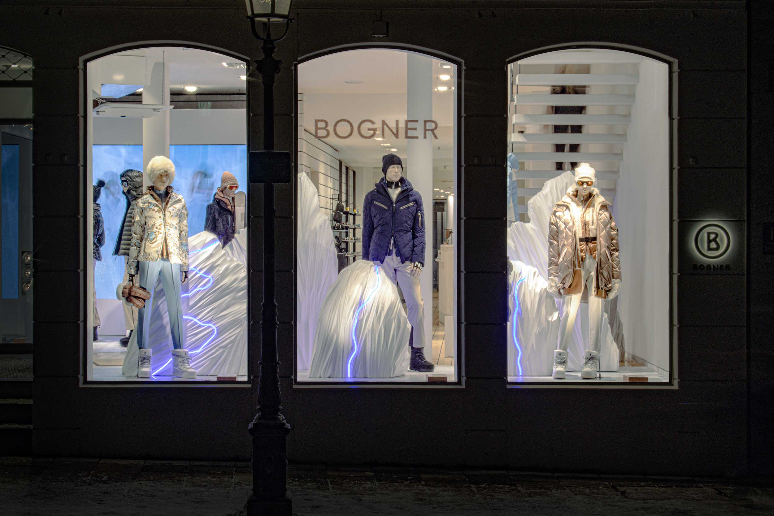 Bogner-Schaufenster bei Nacht mit winterlich gekleideten Mannequins und Lichtinstallation