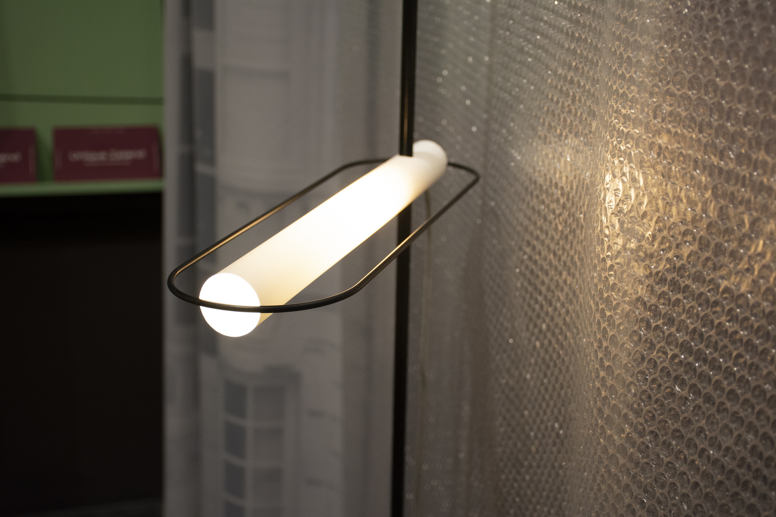 Ringförmige Pendelleuchte leuchtet vor einer Wand mit Luftpolsterfolien-Optik.