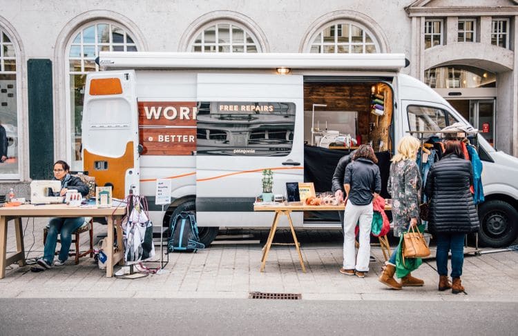 Patagonia „Worn Wear“-Reparatur-Truck mit Kleiderständer und Näharbeit auf der Straße