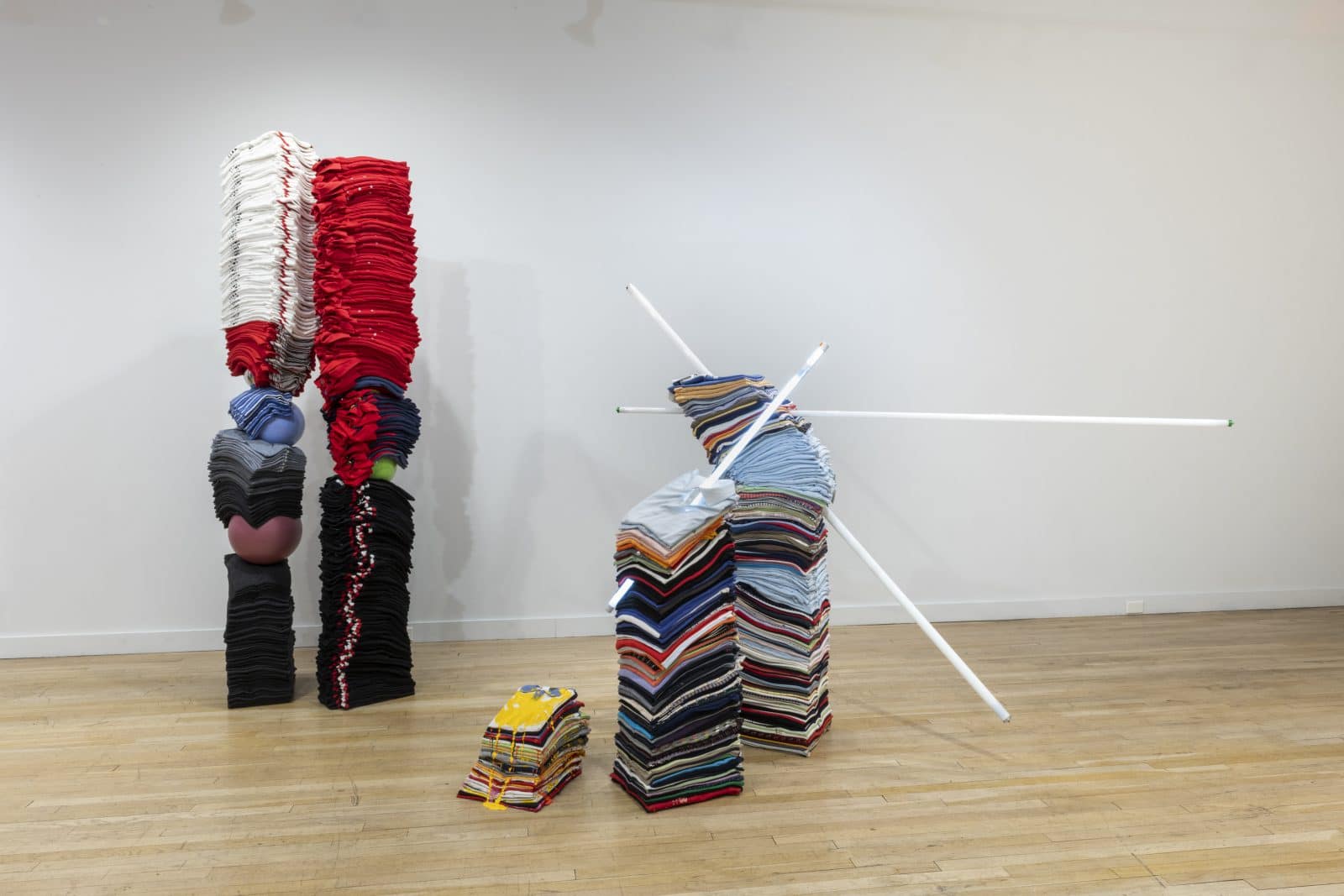 Installationsansicht: turmartige Skulpturen aus gestapelten Kleidungsstücken bei der CUE Art Foundation