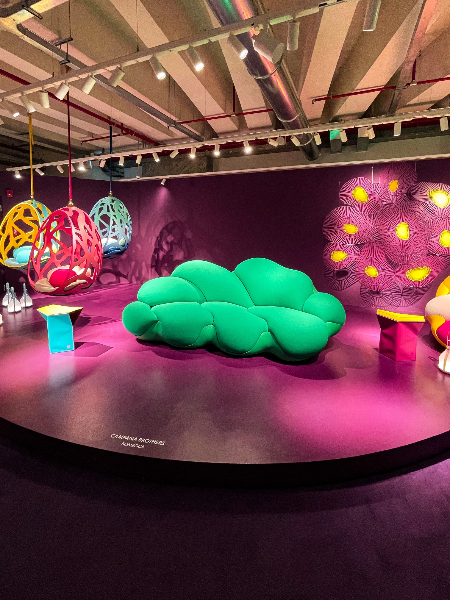Campana Brothers' green “Bomboca” sofa, surrounded by colourful hanging seating objects in a pink setting