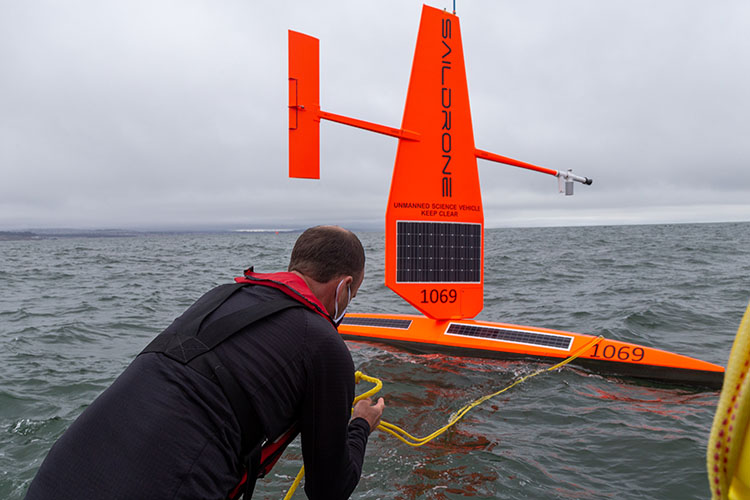 Saildrone employee wearing face mask deploys vehicle in Pacific Ocean