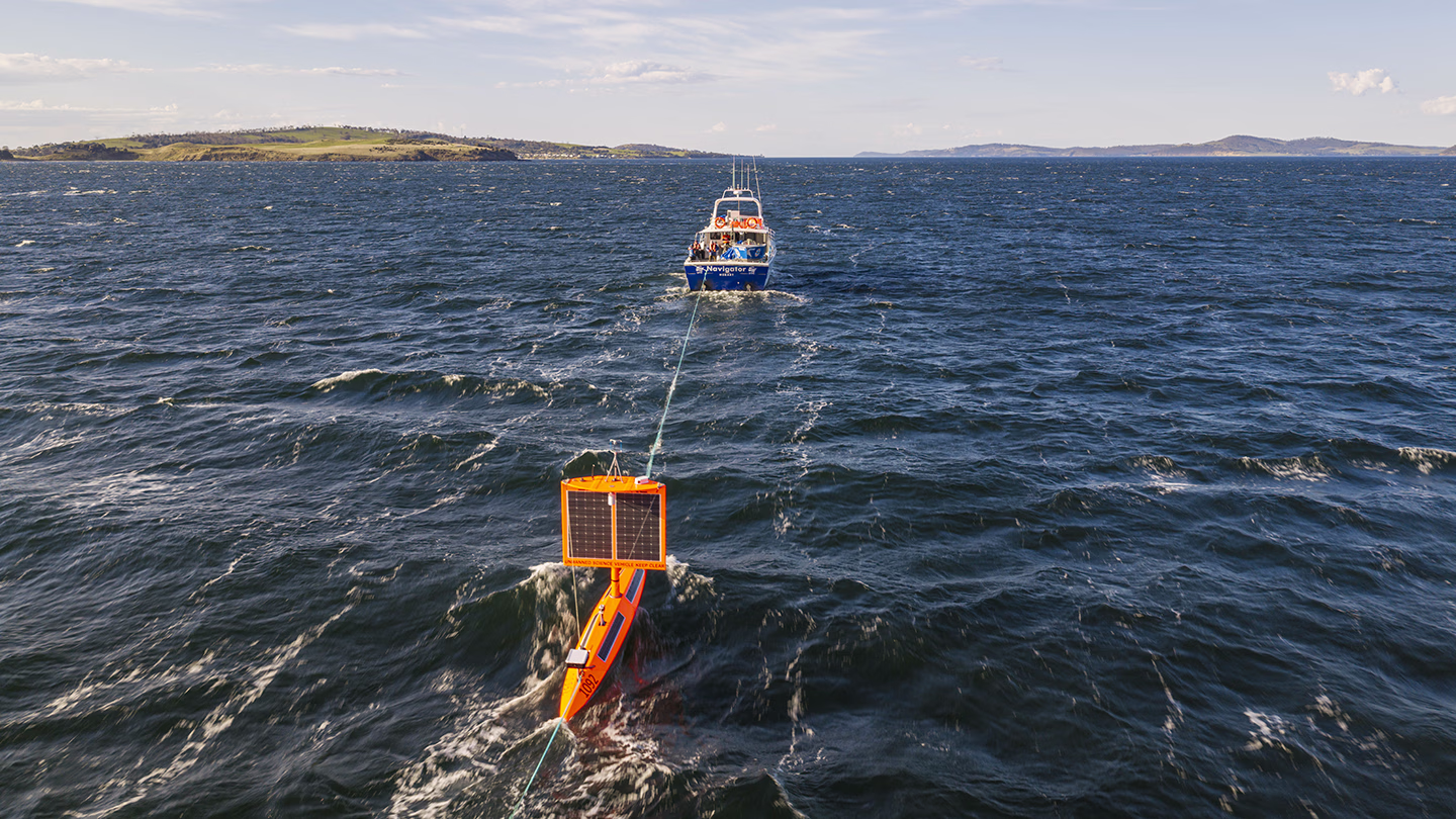 Saildrone Explorer SD-1092 being towed out from Hobart, Australia, with the ocean horizon in the distance.