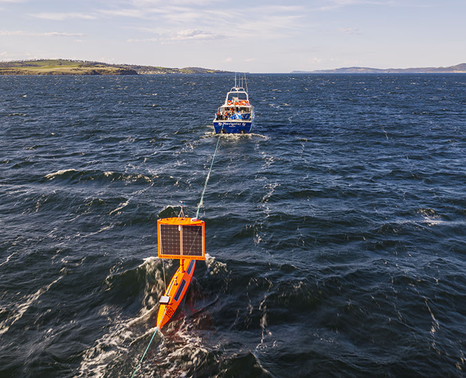 Saildrone Explorer SD-1092 being towed out from Hobart, Australia, with the ocean horizon in the distance.