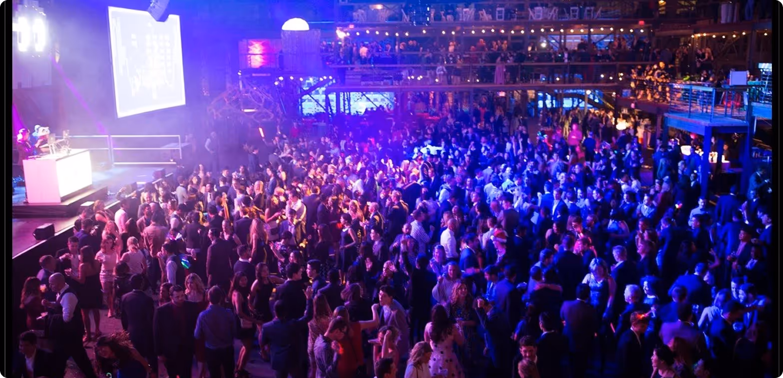 Large crowd dancing in a club under blue and purple light