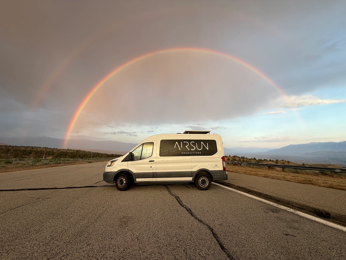 The Airsun Productions van parked on an open road under a double rainbow