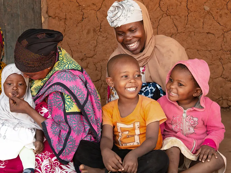 Photo of a family laughing together in a village in Kenya, which was visited by community health workers providing information and awareness about NTDs.