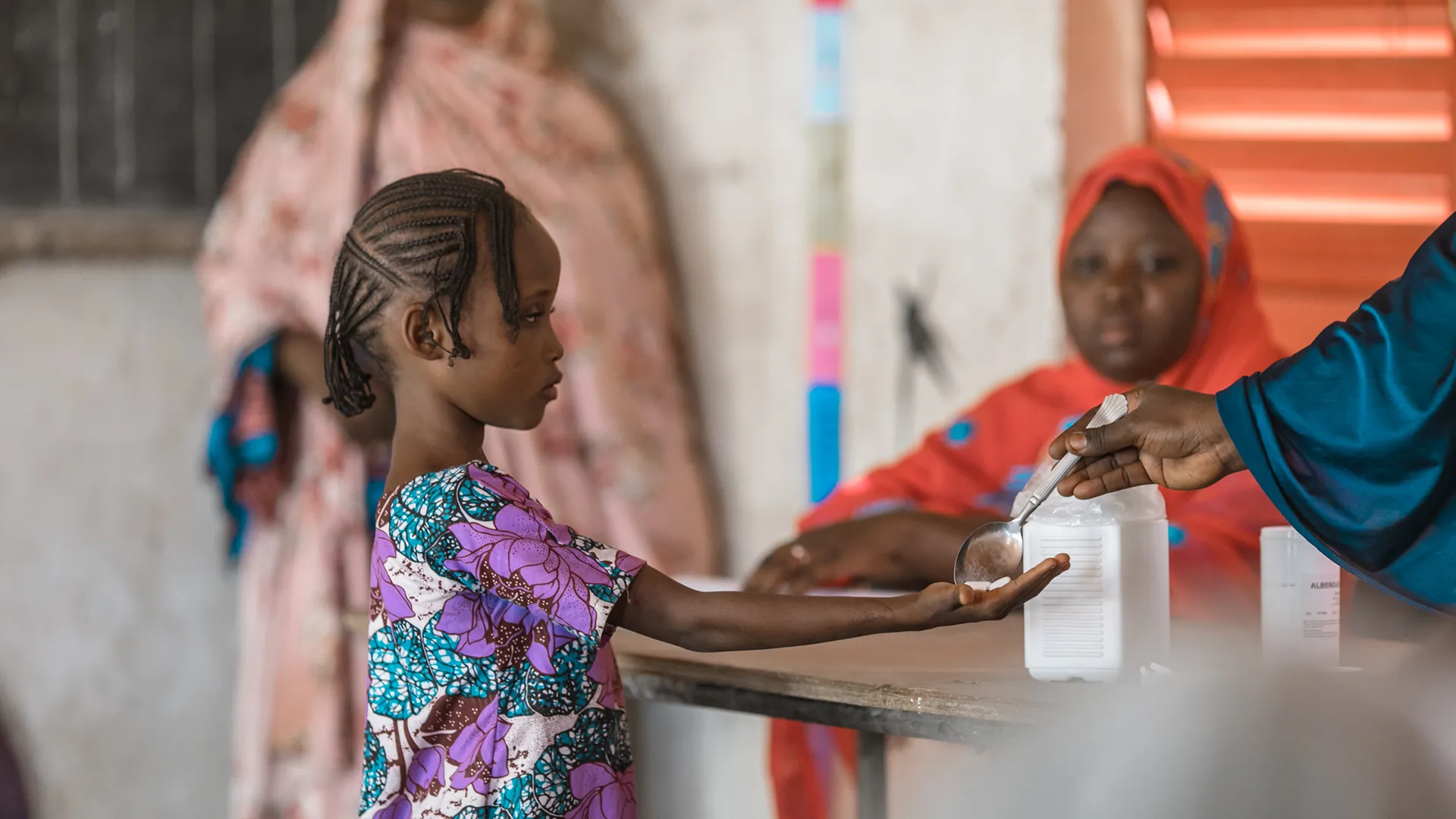 Photo of a young child receiving schistosomiasis medicine during a mass drug administration (MDA) campaign in a school in N’dounga Tarey, Niger.