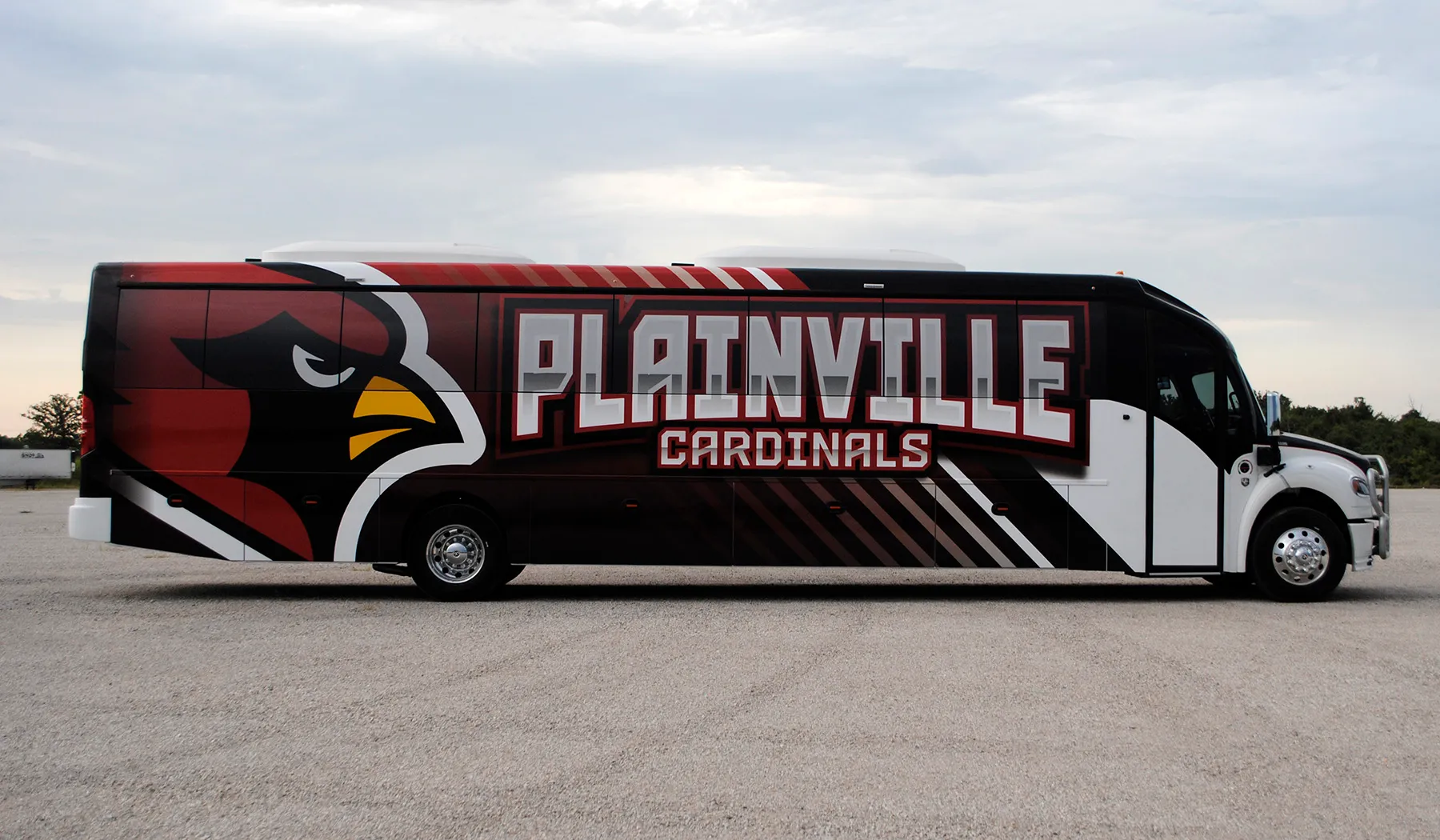 Side view of a Plainville Cardinals Ultra Coachliner wrapped by National Wrap Co.
