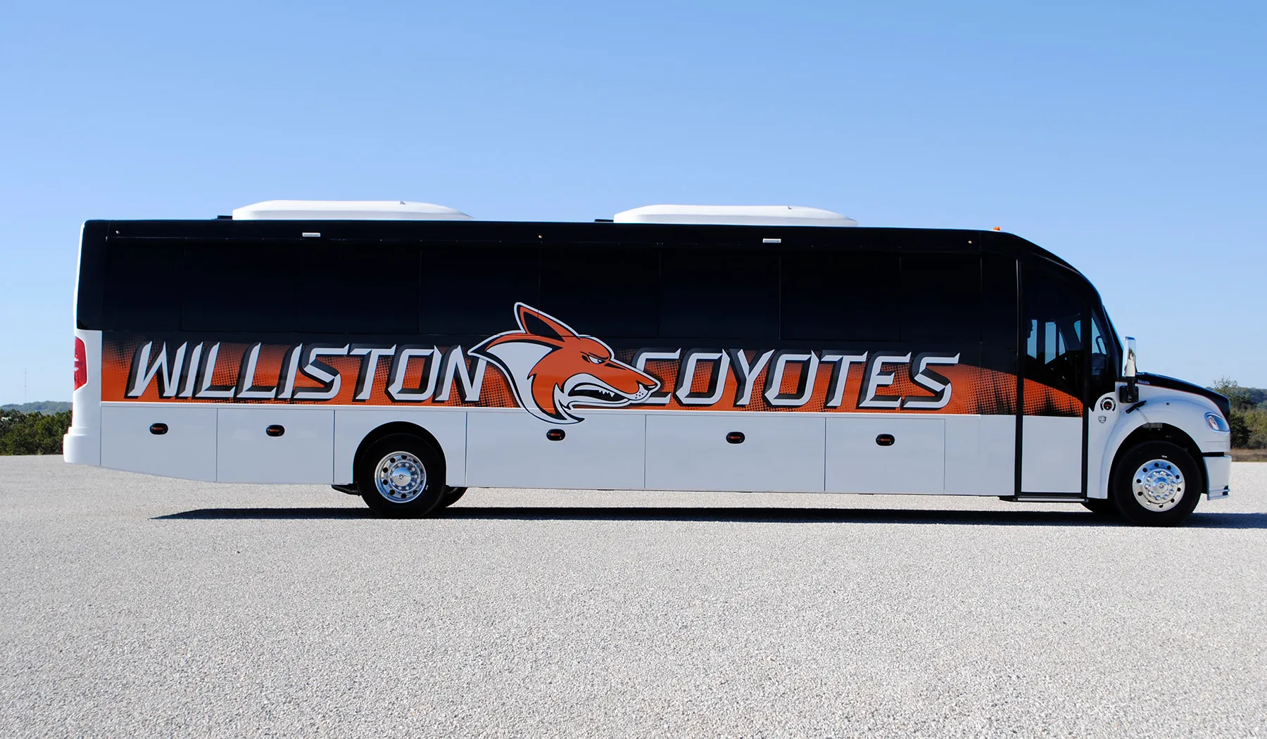 Side view of a Williston Coyotes Ultra Coachliner wrapped by National Wrap Co.