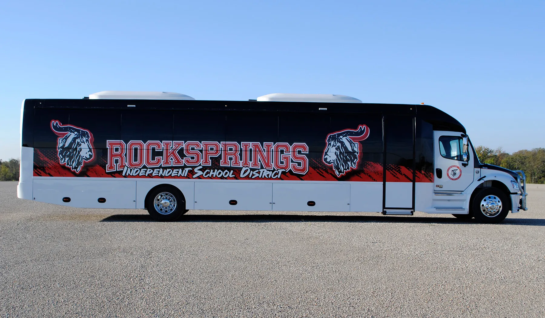 Side view of a Rock Springs Independent School District Ultra Coachliner wrapped by National Wrap Co.