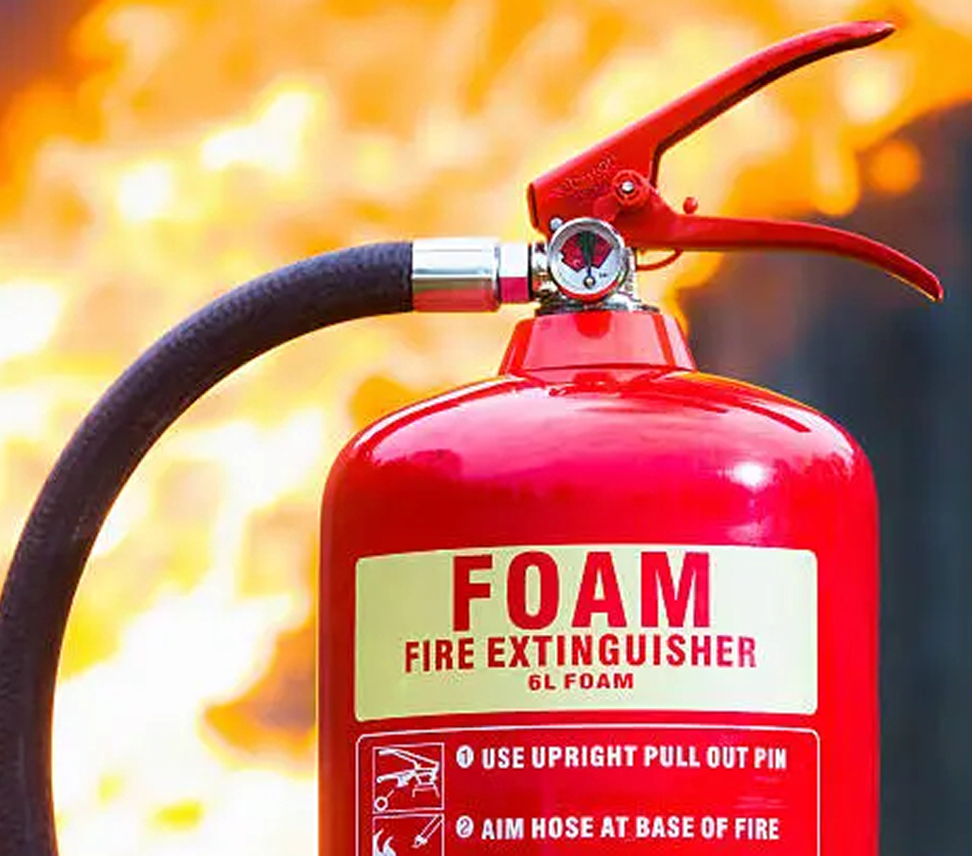 Close-up of red foam fire extinguisher with instructions and flames in the background.