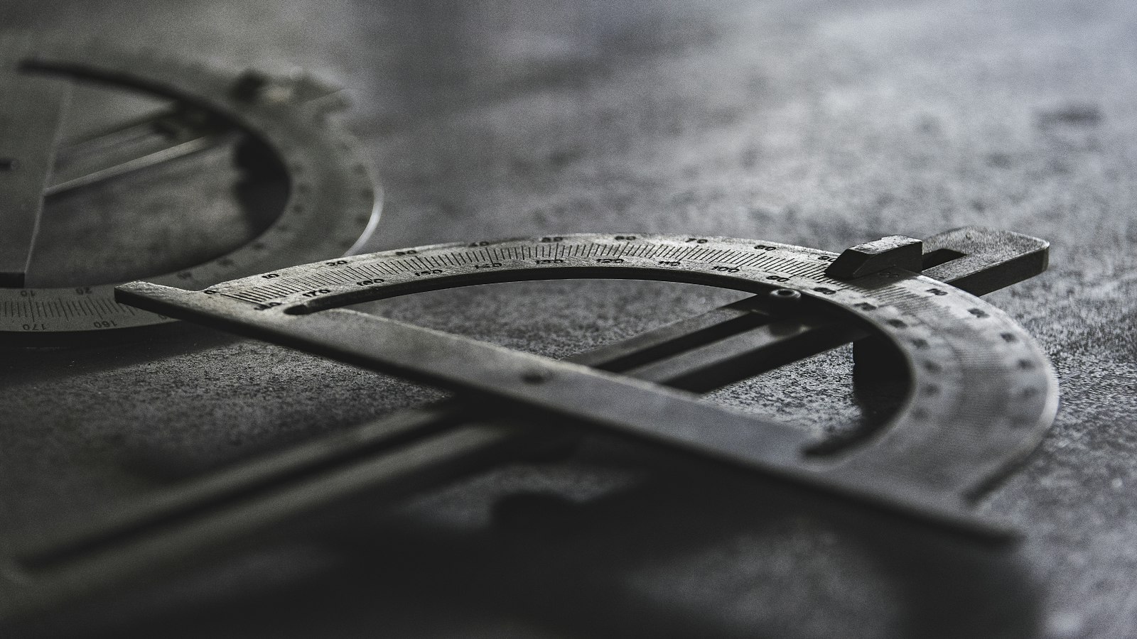 Compas de précision en métal photographié en gros plan, en noir et blanc, sur un fond épuré et sans décor