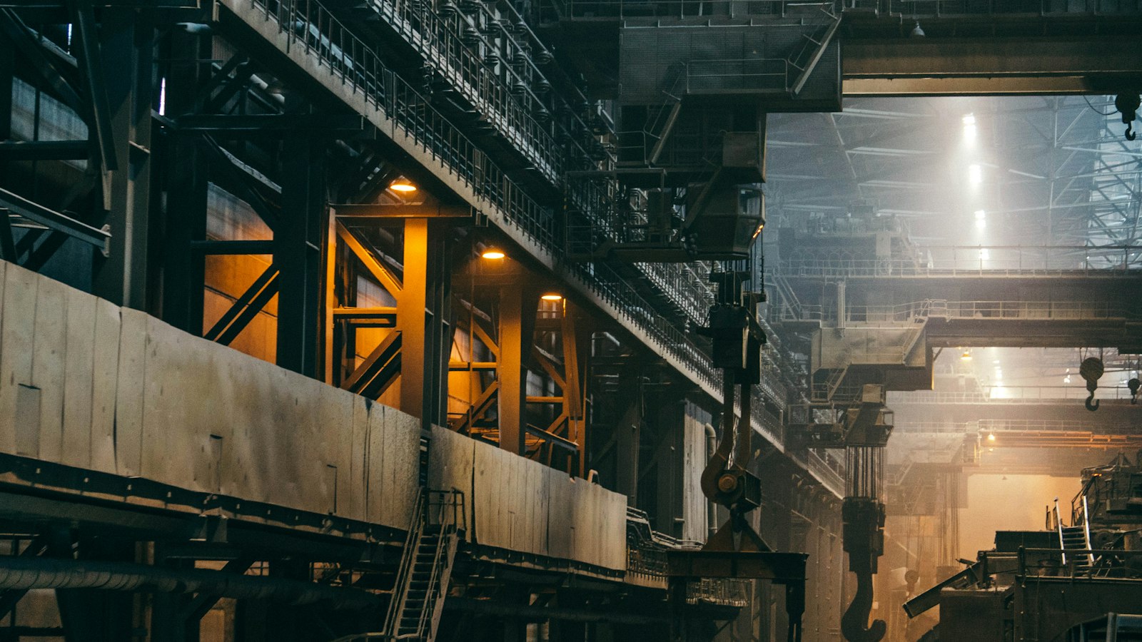 Intérieur d'une vaste usine de métallurgie, charpente d'acier et ligne de production vues en perspective