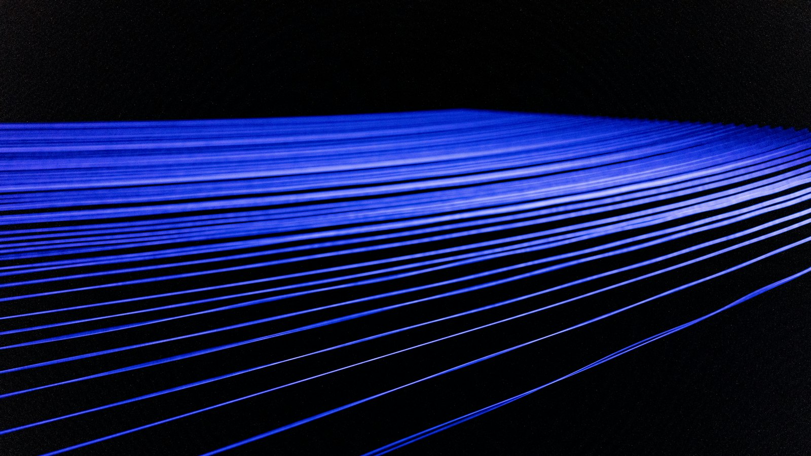 Fines bandes de lumière bleue au centre d’un fond noir, dans une composition minimaliste
