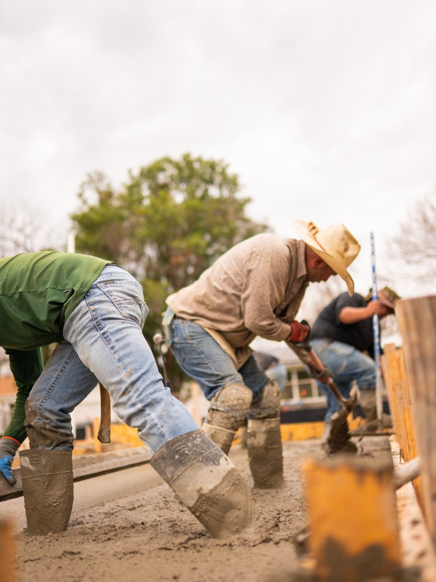 Workers pouring custom pool concrete during construction and installation project