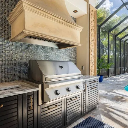 Custom patio outdoor kitchen with stainless steel grill and tile backsplash