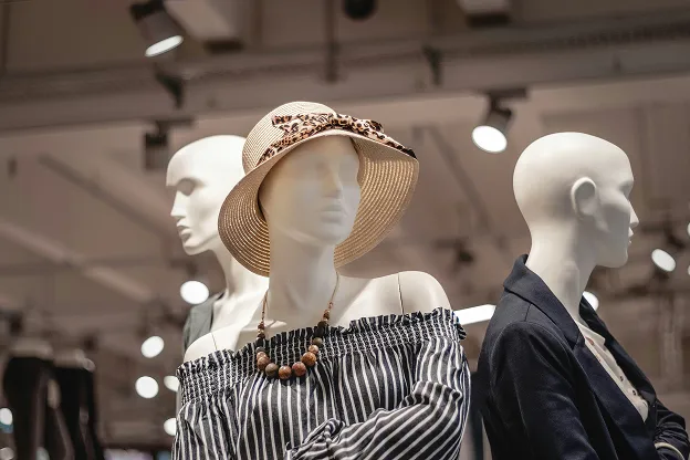 Three mannequins dressed in stylish clothing, one wearing a striped off-shoulder top and a hat.