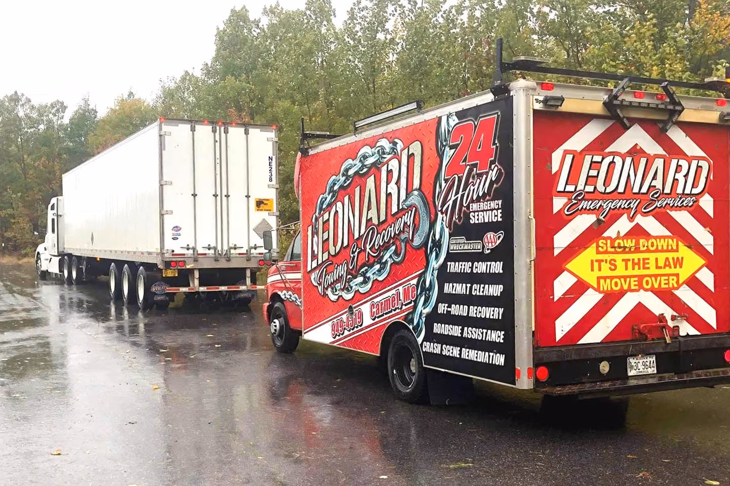 Leonard Emergency Services tow truck and semi-trailer on a wet roadside.