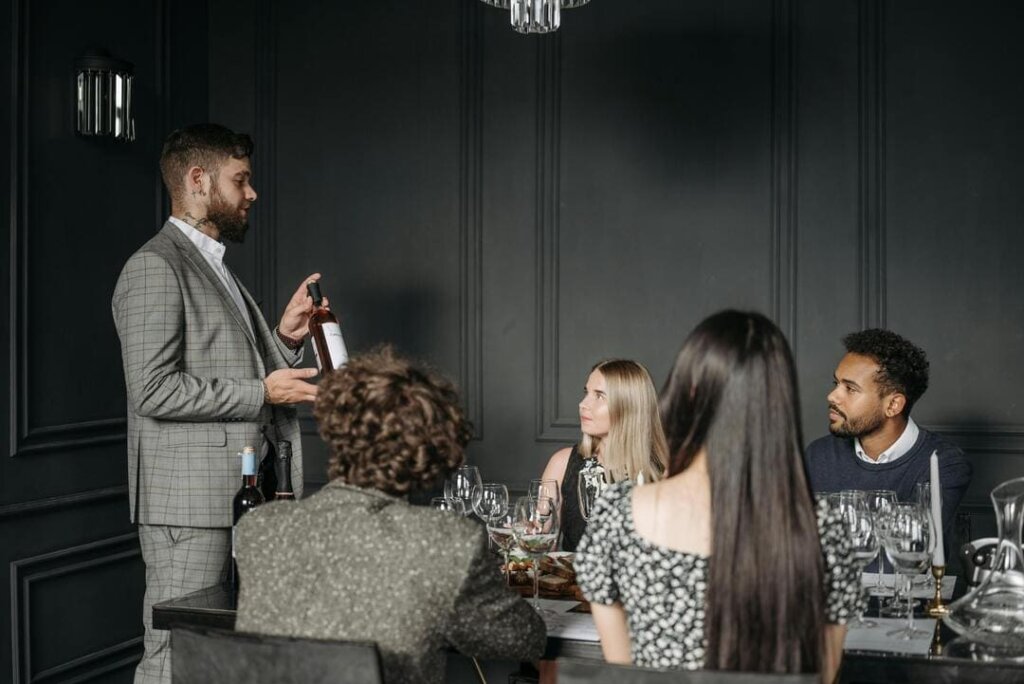 Sommelier asesorando a clientes en un restaurante sobre la selección de vinos