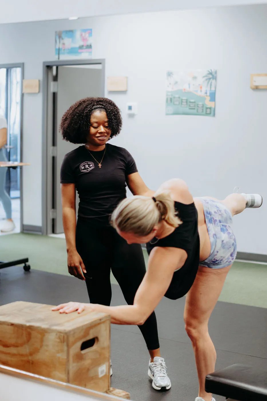 Patient performing a hip hinge on a plyo box supervised by a physical therapist