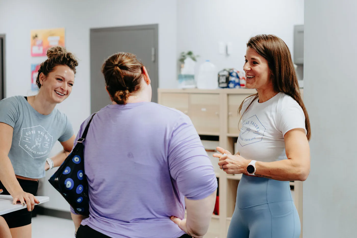 Two Core Values Physical Therapy staff laughing with a patient in the lobby