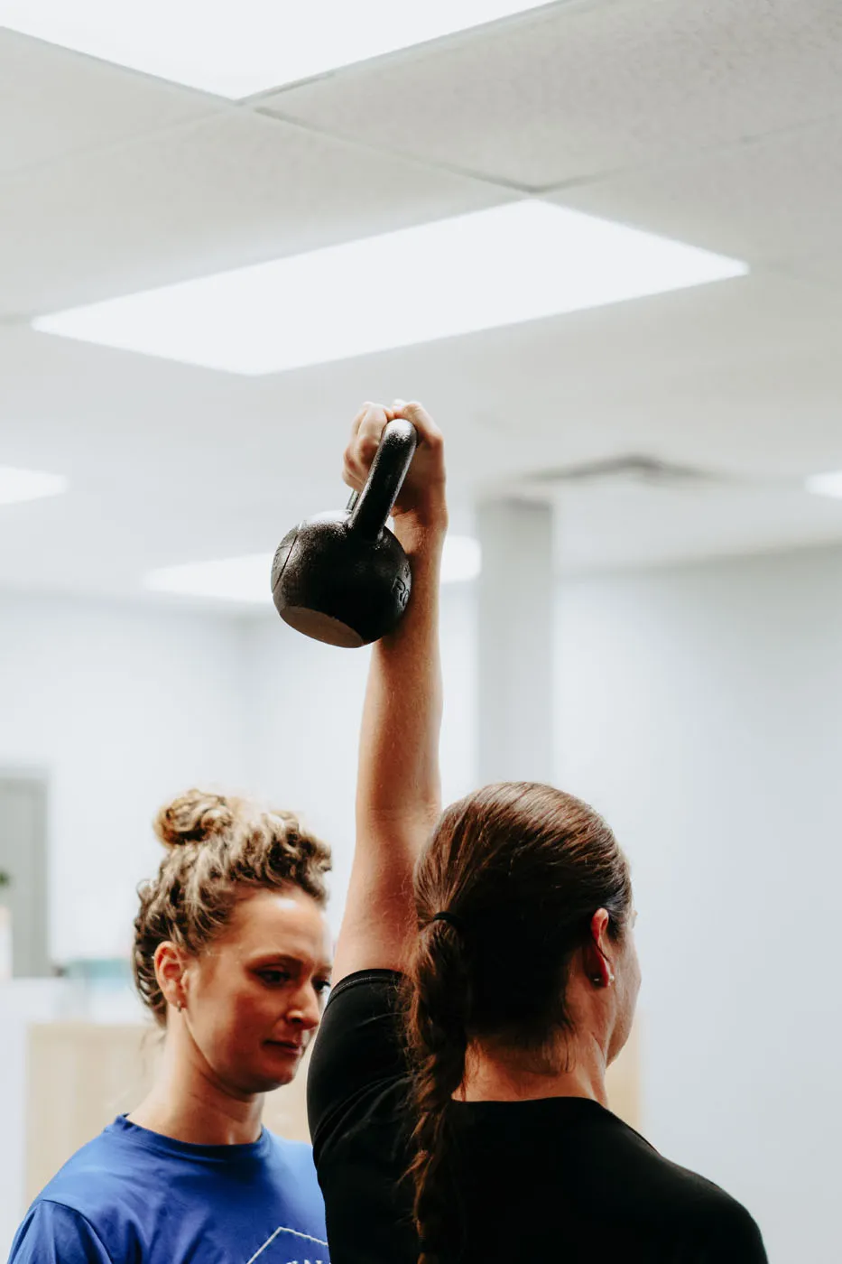 Patient performing an overhead kettlebell press during physical therapy