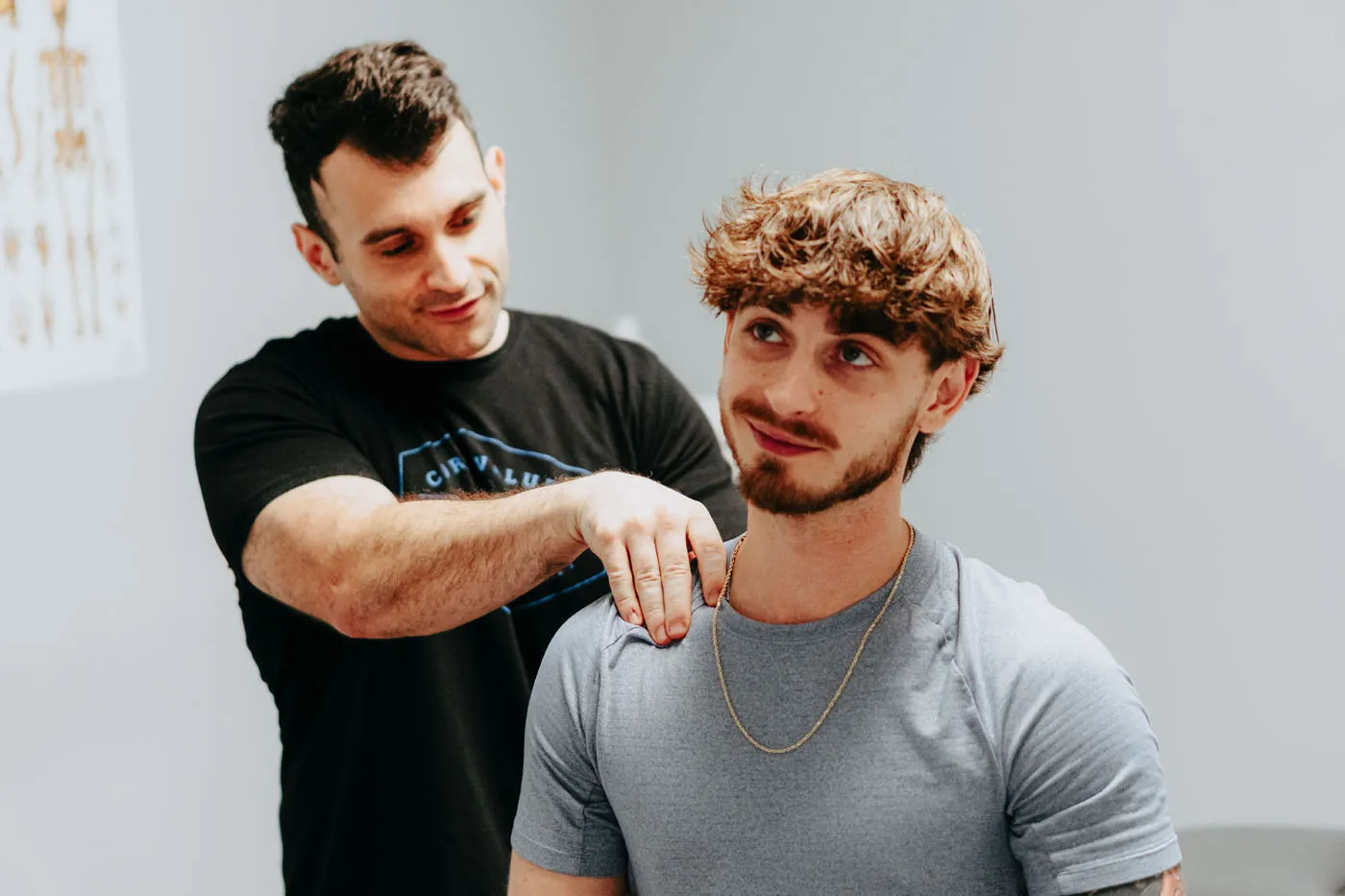 Physical therapist performing a shoulder assessment on a smiling patient