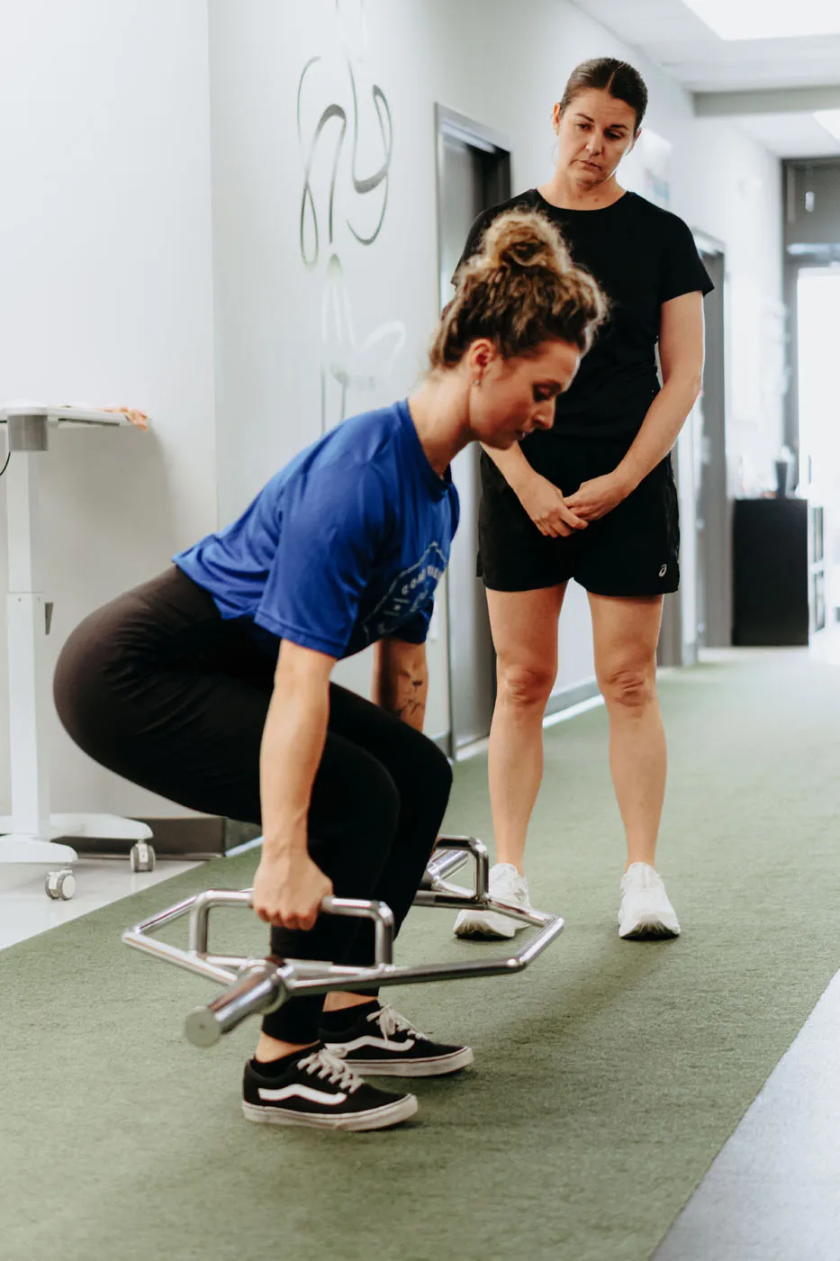 Patient performing a hex bar squat under physical therapy supervision