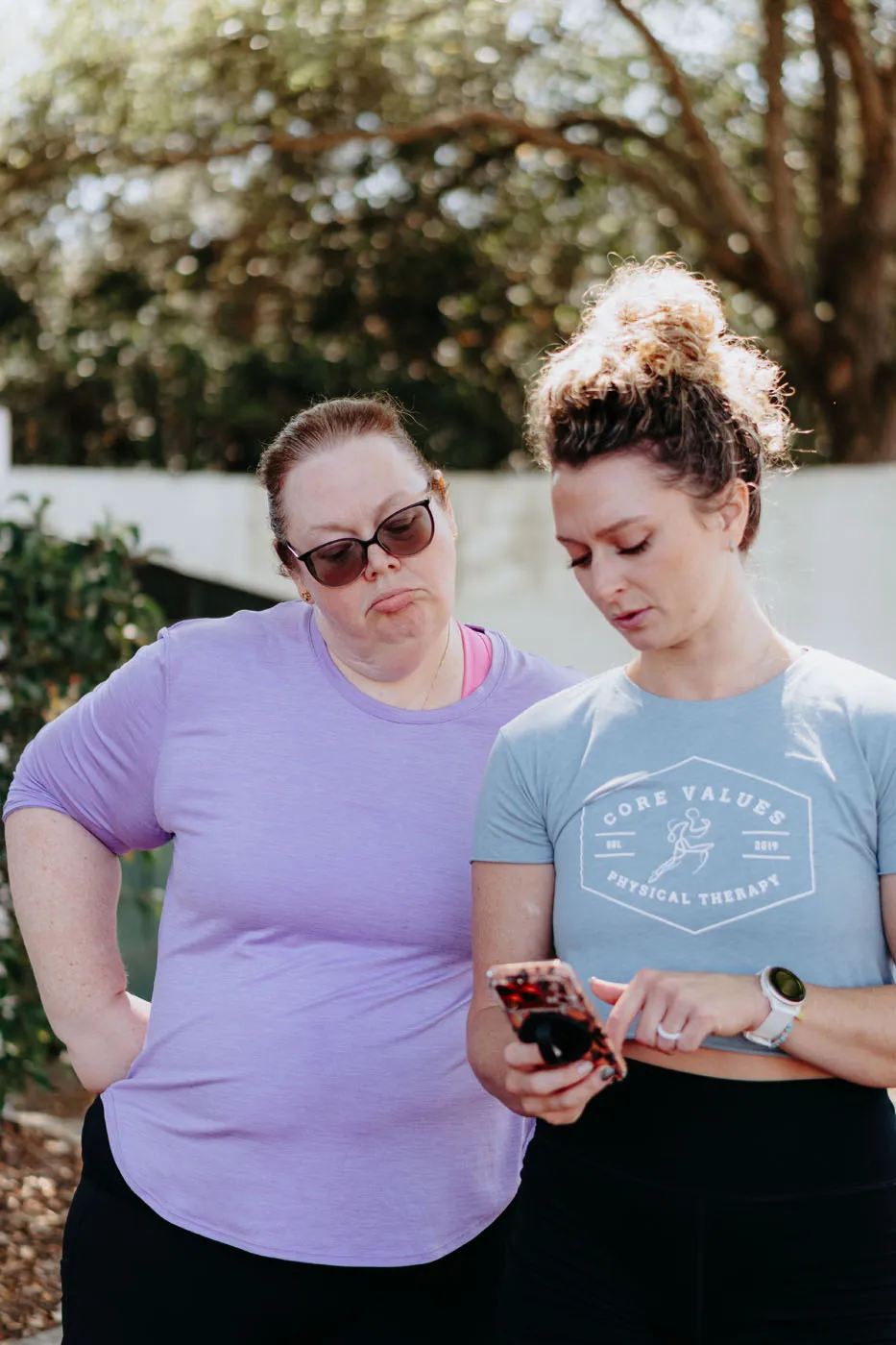 Physical therapist reviewing run data on a phone with a patient after an outdoor session
