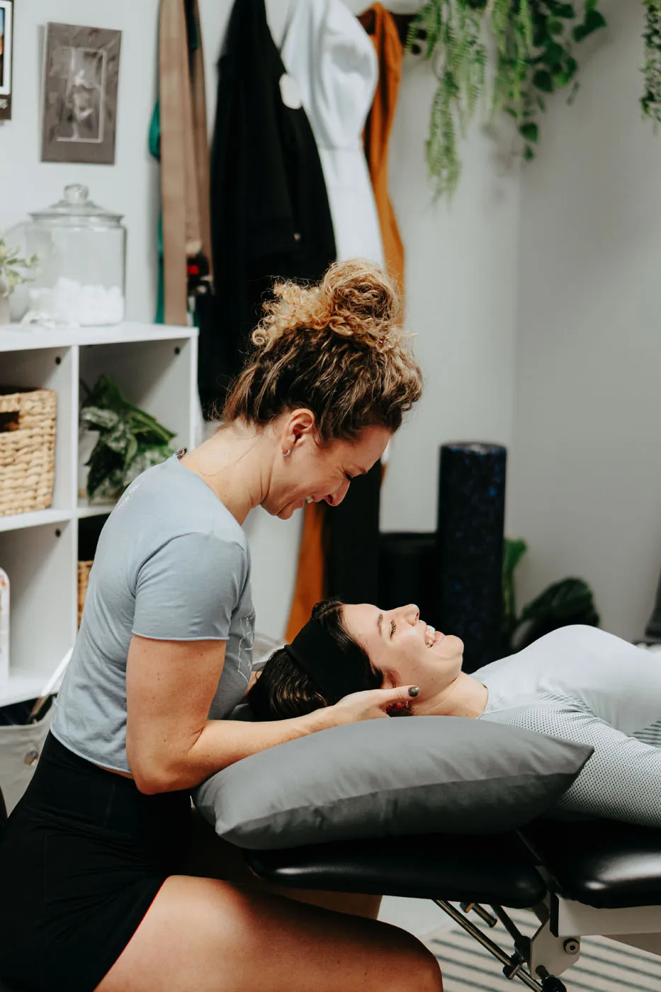 Physical therapist laughing while performing cervical manual therapy on a prone patient