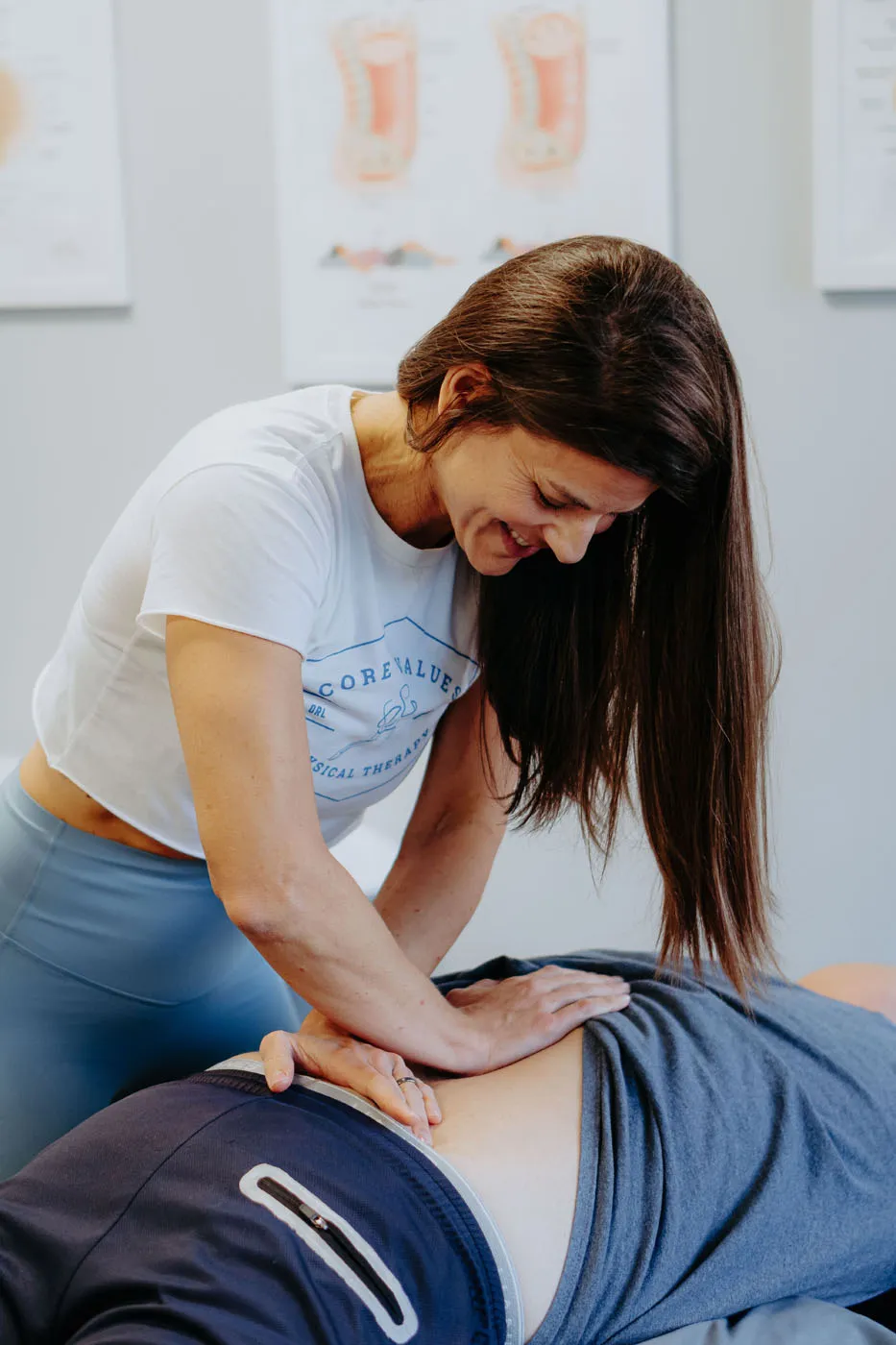 Physical therapist smiling while performing lumbar manual therapy on a patient