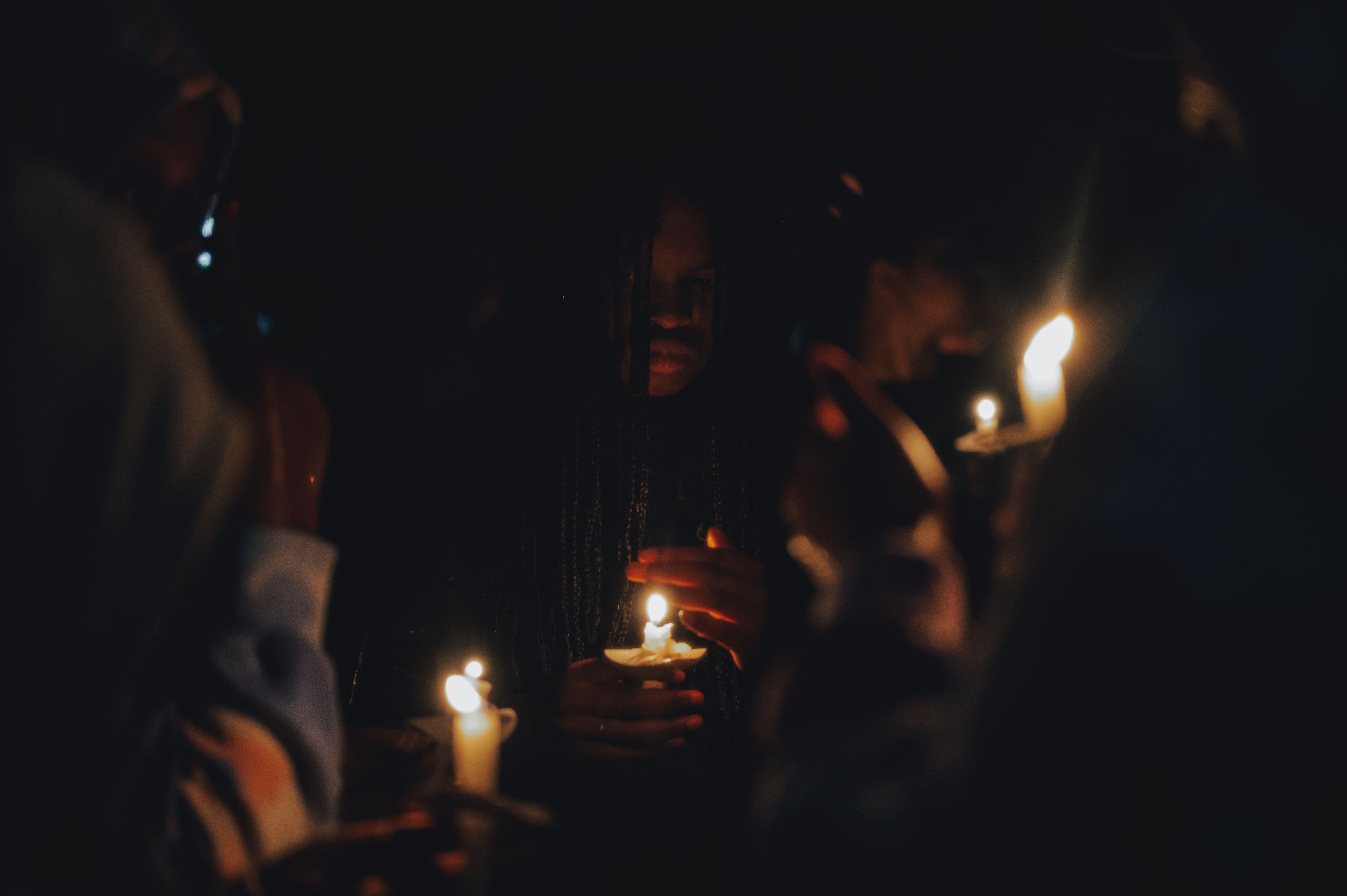 People holding lit candles in a dark room