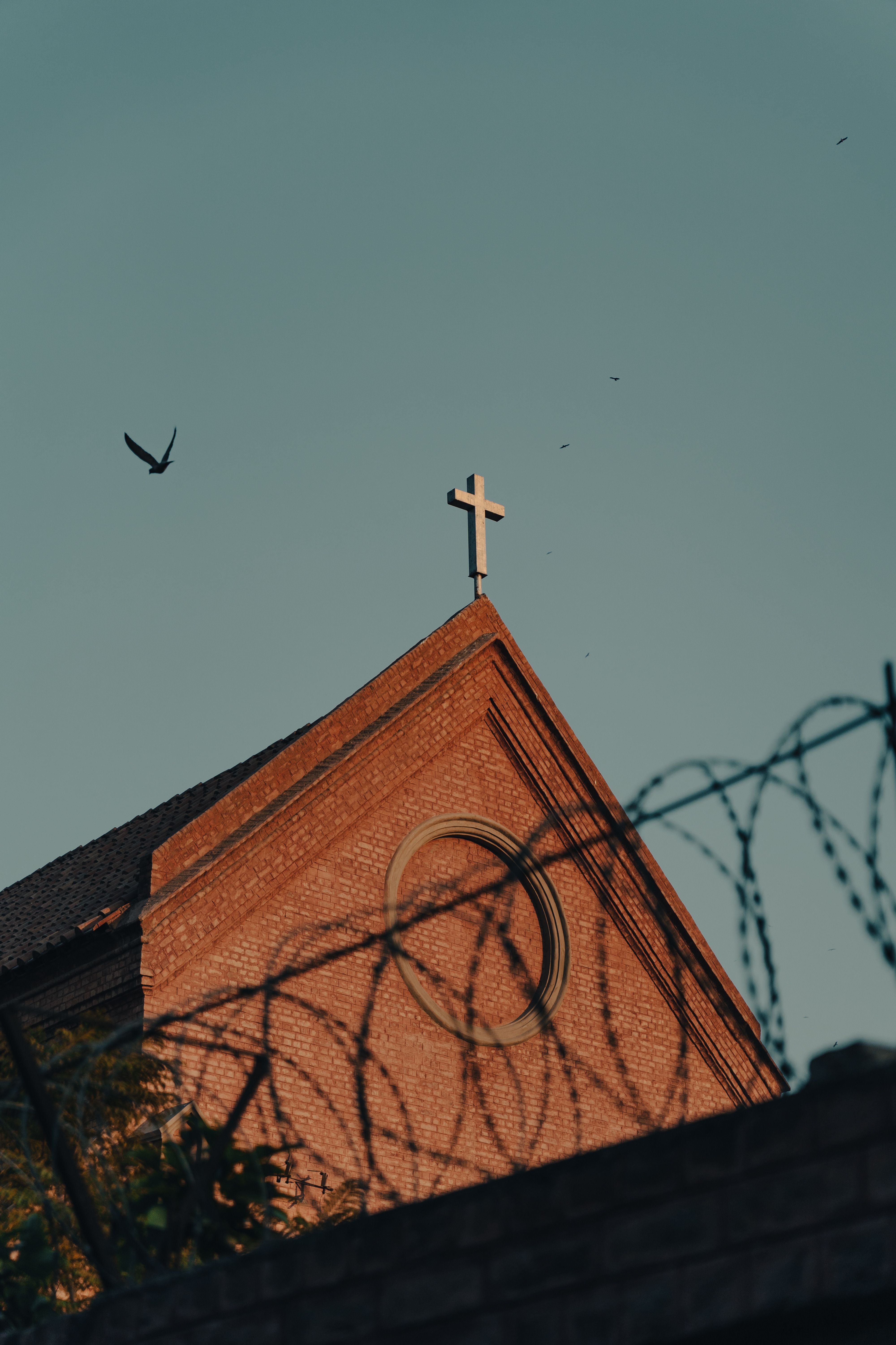 Church steeple with a cross behind barbed wire