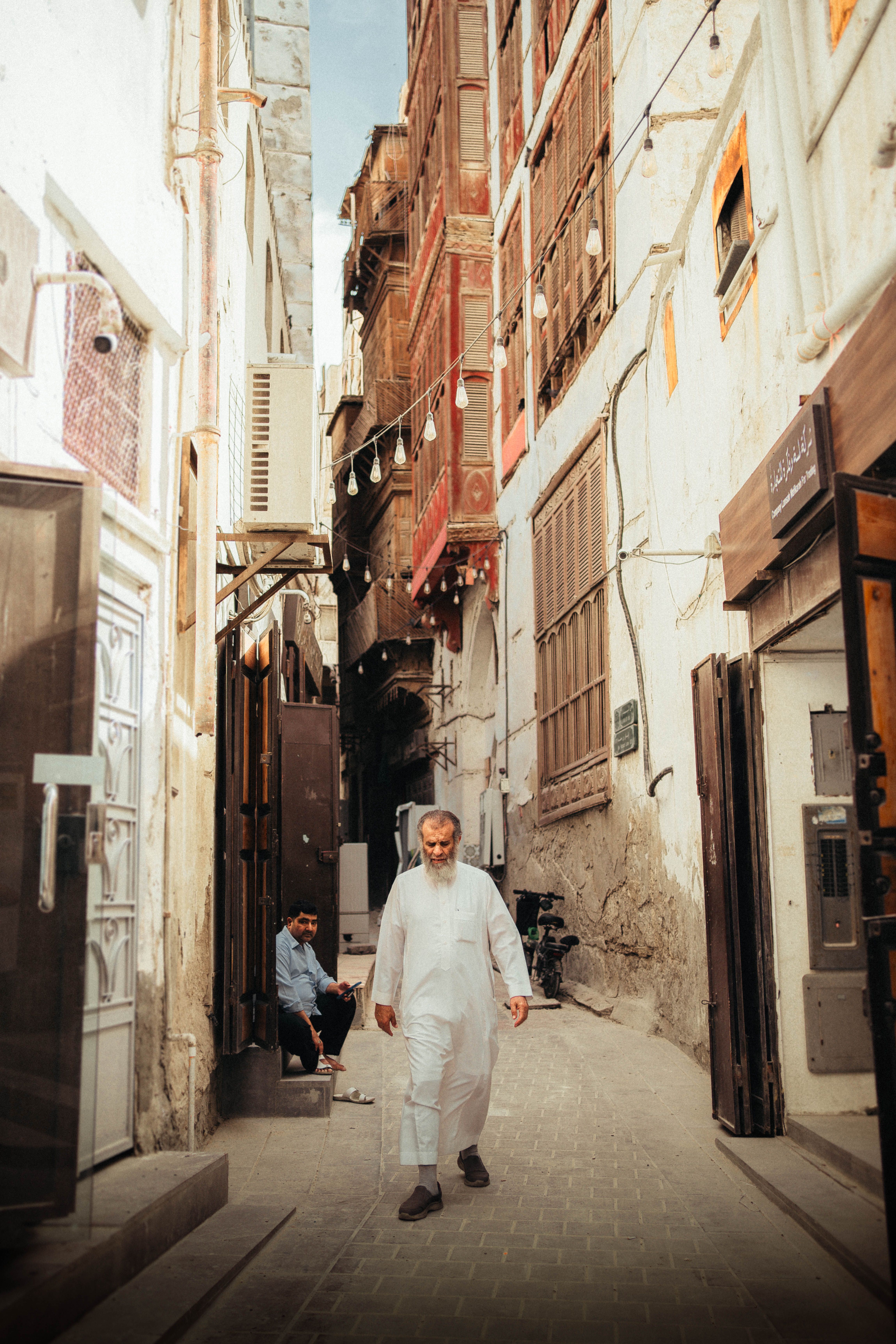 An elderly man walking through a narrow Middle Eastern alley