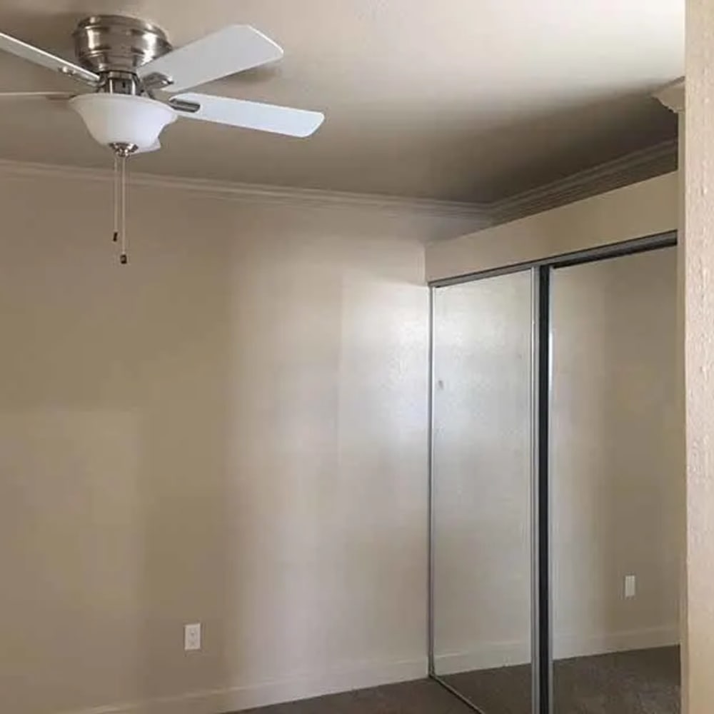 Unfurnished bedroom with closet with mirrored doors and ceiling fan