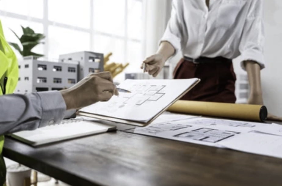 Office scene with two people discussing architectural drawings