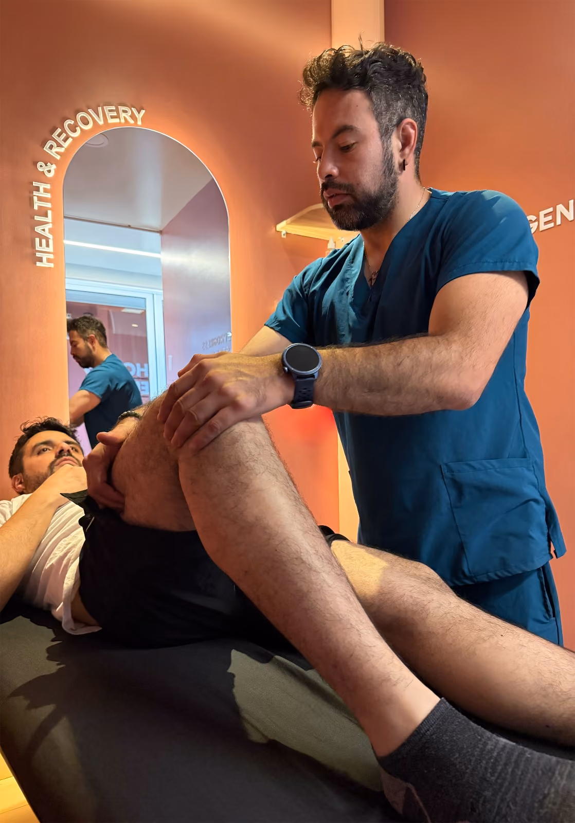 Fisioterapeuta examina la rodilla de un paciente acostado en una camilla en clínica de salud.