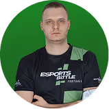 Man in a black esports jersey with arms crossed, green background.