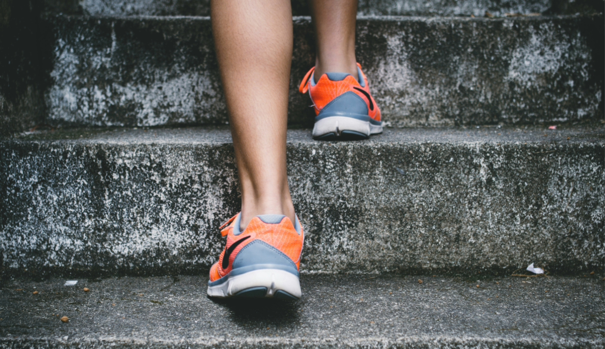 Person's feet walking up stairs in sneakers
